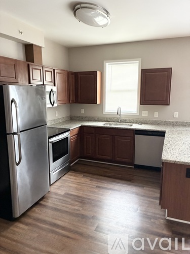 A kitchen with wooden cabinets and a stainless steel refrigerator.