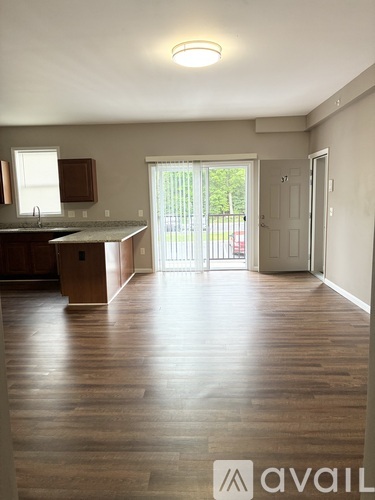 A spacious room with wooden floors and a kitchen area with a sink and cabinets.