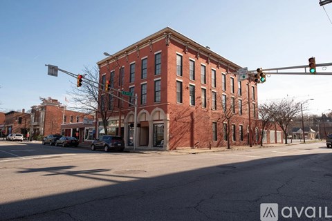 A red brick building is located on a street corner with a traffic light above it.