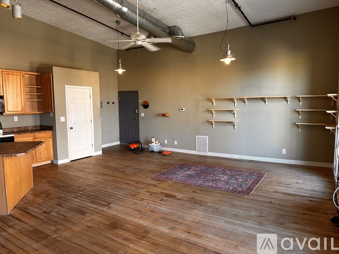 A room with wooden floors and a kitchen area with a counter and cabinets.