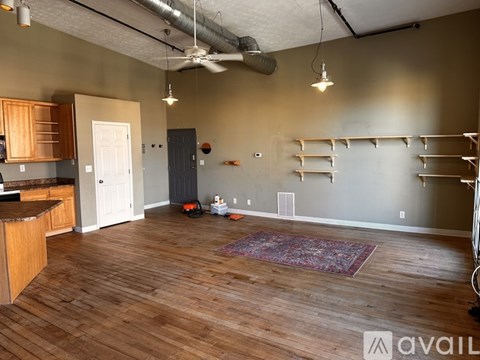 A room with wooden floors and a kitchen area with a counter and cabinets.