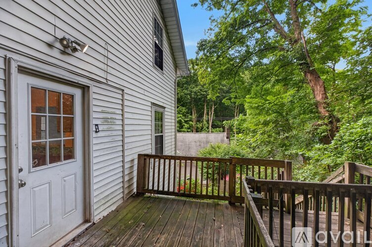 A deck with a white door and a window is surrounded by trees.