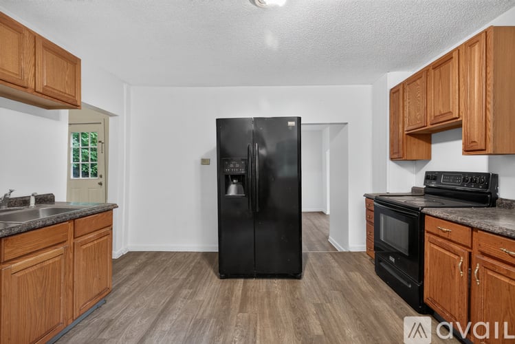 A kitchen with wooden cabinets and a black fridge.