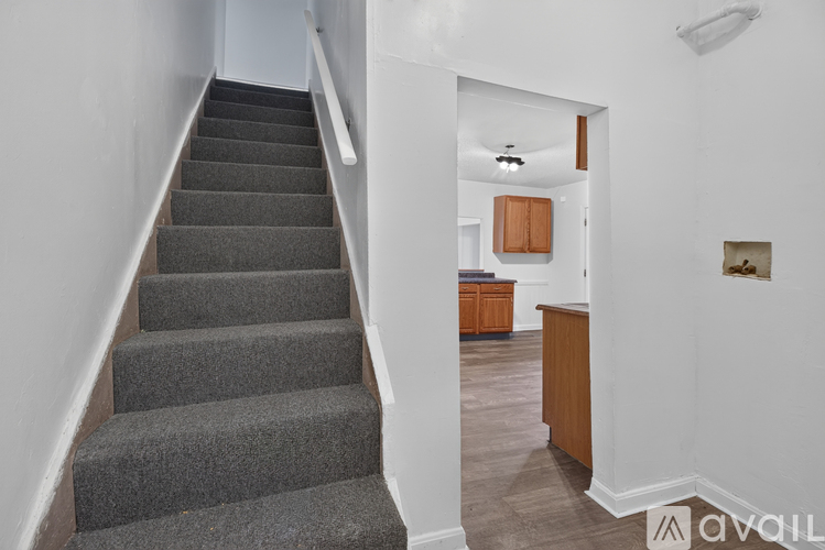 A staircase with a carpeted runner leads to a kitchen area.