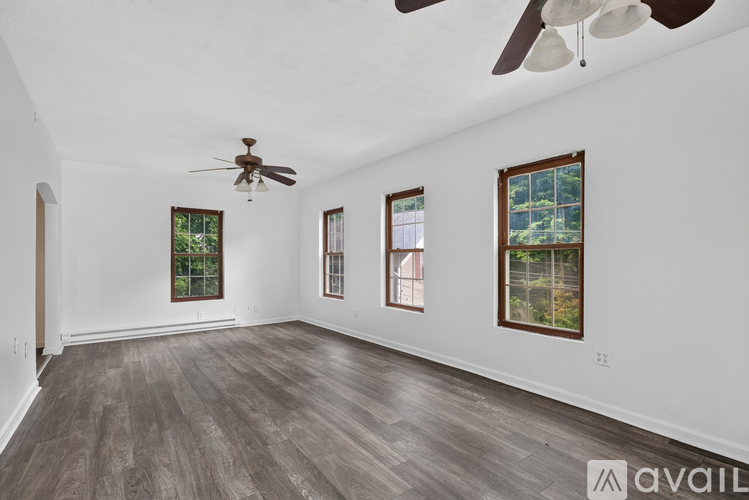 A spacious room with a ceiling fan and three windows.