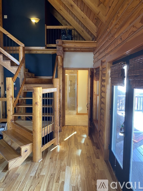 A wooden staircase with a glass railing leads to a landing with a door.