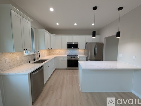 A modern kitchen with white cabinets and stainless steel appliances.