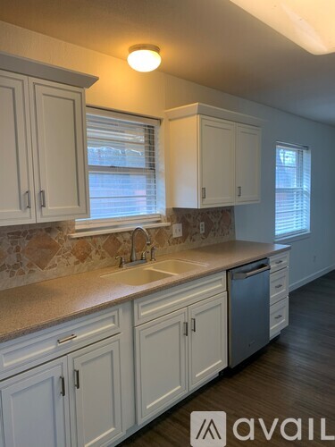 A kitchen with white cabinets and a stone backsplash.