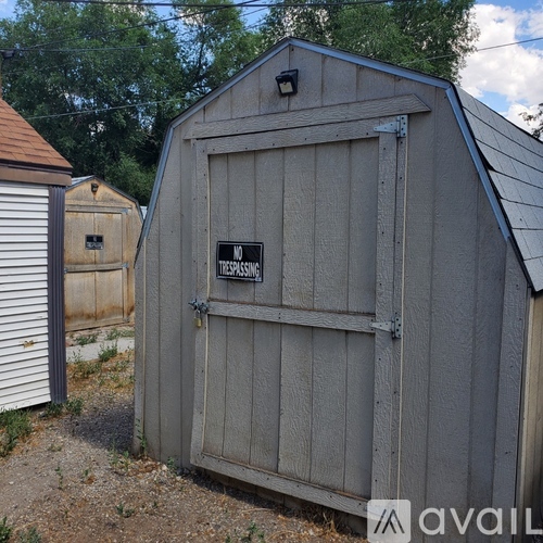 A small wooden shed with a door that has a sign on it.
