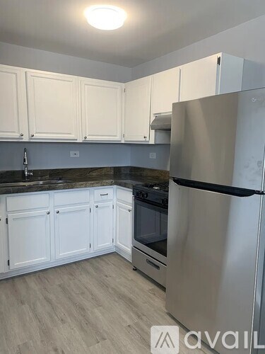 A kitchen with white cabinets and a stainless steel refrigerator.
