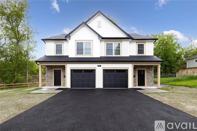 A two-story house with a black garage door is for sale.