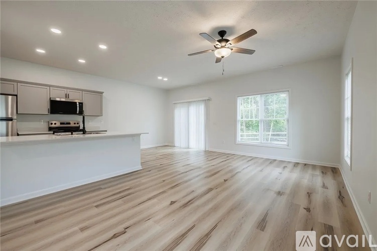 A spacious room with wooden flooring and a ceiling fan.