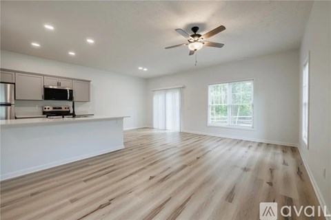 A spacious room with wooden flooring and a ceiling fan.
