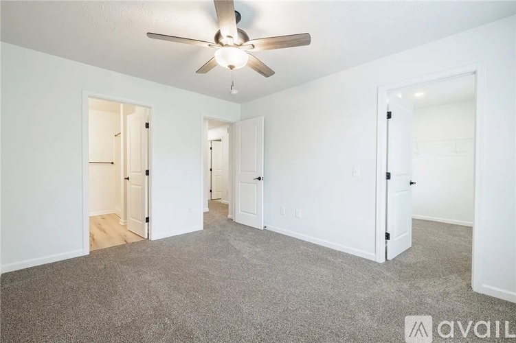 A spacious room with a ceiling fan and carpeted floor.