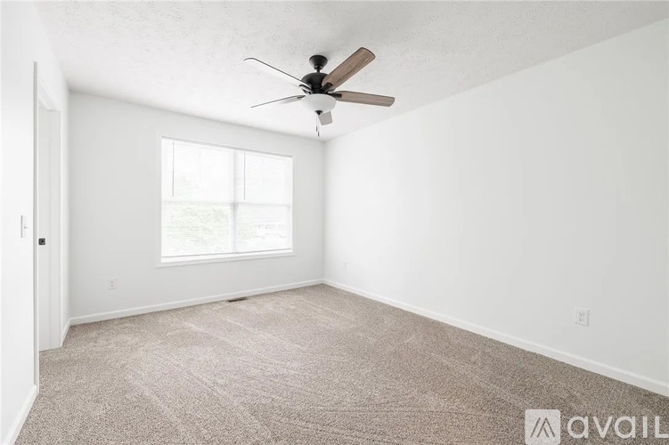 A room with a ceiling fan and carpeted floor.