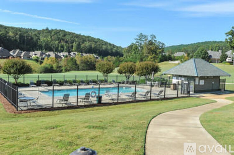 A pool surrounded by a black fence with a small building to the right.