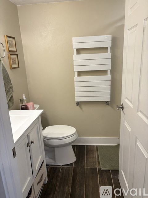 A bathroom with a toilet, a sink, and a towel rack.