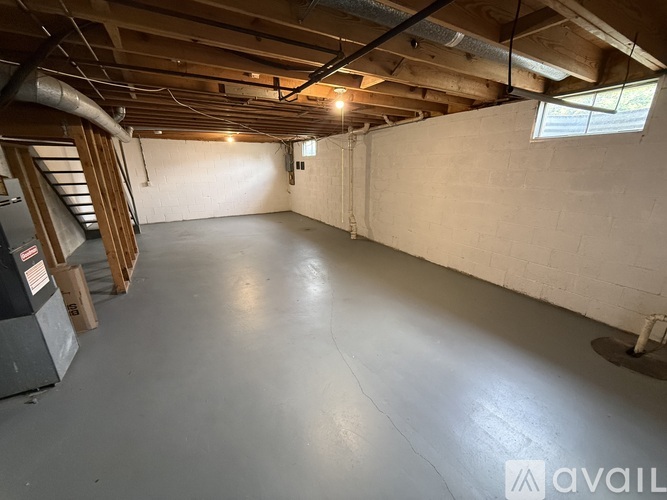 A spacious empty room with a concrete floor and a window on the right side.