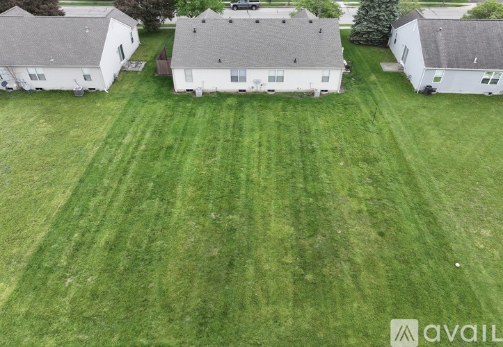 A grassy field with three houses in the background.