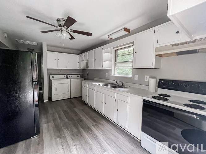 A kitchen with a black fridge and a black stove top oven.