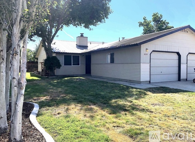 A house with a garage and a tree in front.
