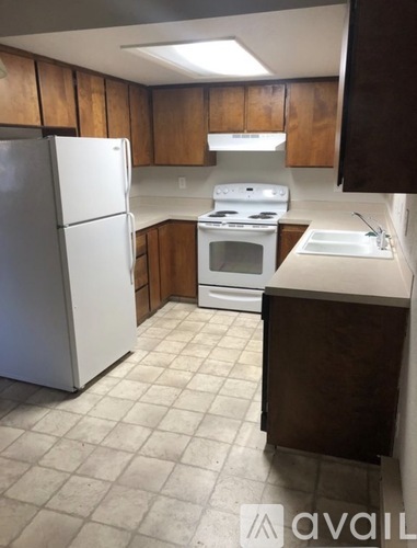 A kitchen with a white refrigerator, white stove, and brown cabinets.