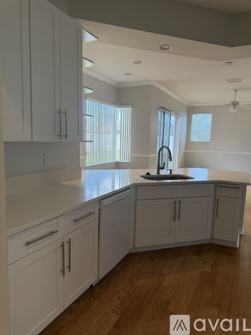 A kitchen with white cabinets and a wooden floor.