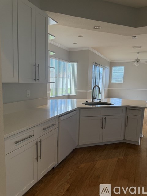 A kitchen with white cabinets and a wooden floor.
