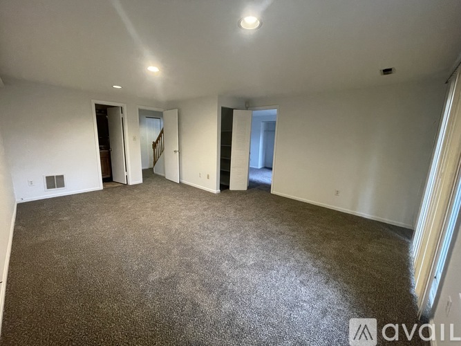 A spacious empty room with carpeted floor and white walls.