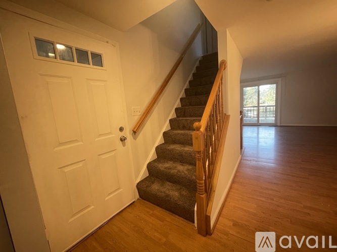 A wooden staircase with a carpeted runner leads up to a door.