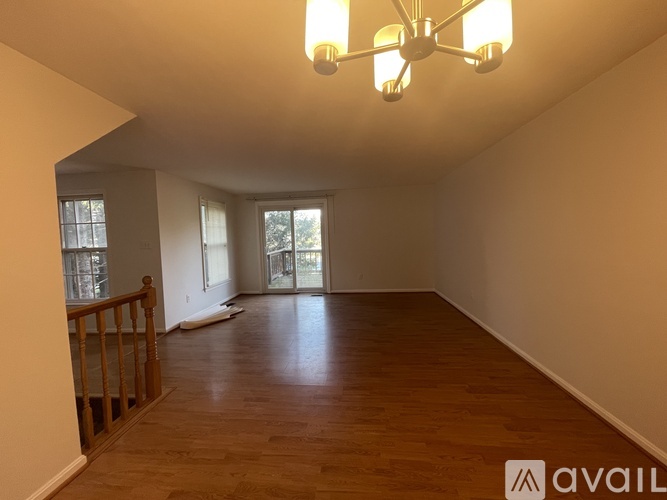 A large empty room with wooden floors and a chandelier.
