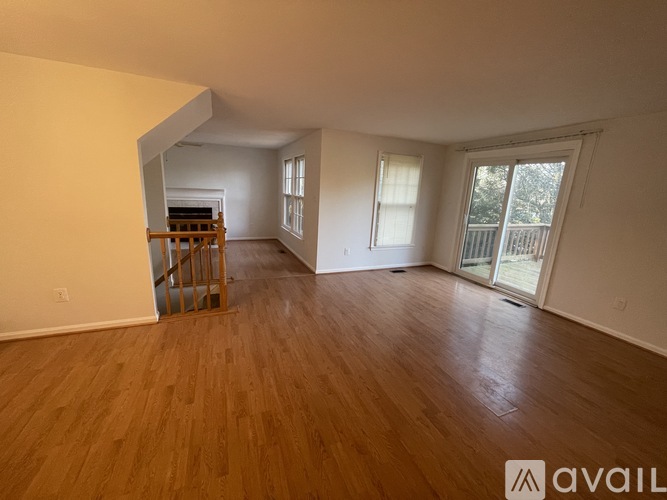 A room with wooden flooring and a staircase leading to the upper level.