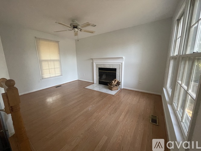 A living room with a fireplace and a ceiling fan.