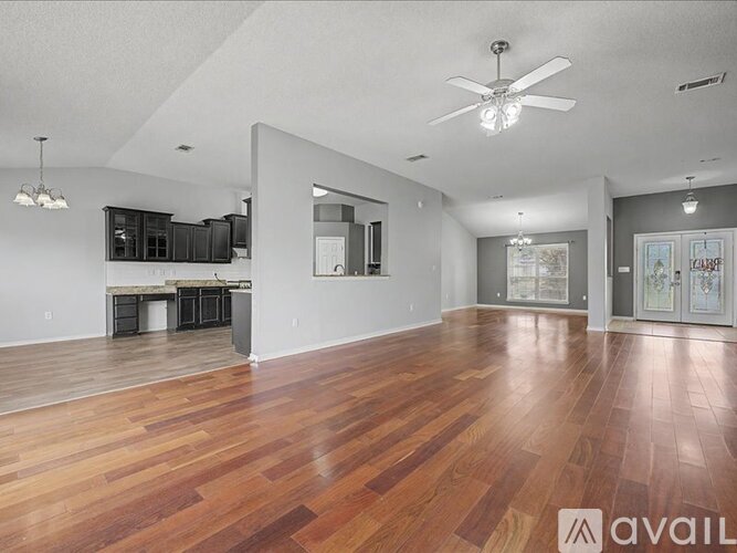 A spacious room with wooden floors and a ceiling fan.