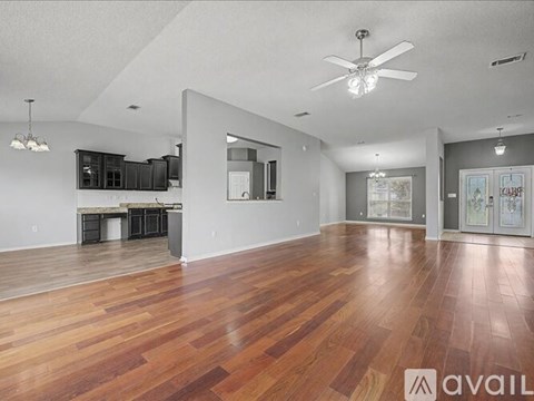 A spacious room with wooden floors and a ceiling fan.