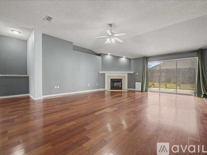 A spacious room with wood flooring and a fireplace.