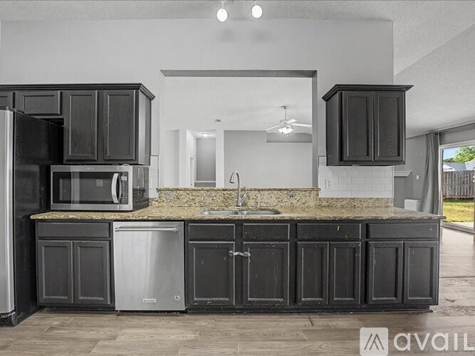 A kitchen with black cabinets and a granite countertop.