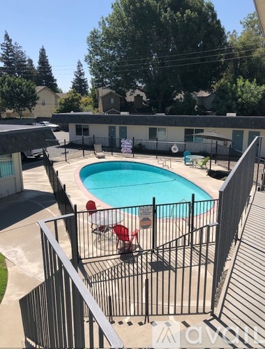 A pool surrounded by a black fence with a red chair in the middle.