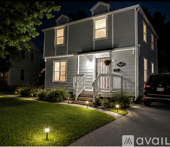 A house with a well-lit front porch and a car parked in the driveway.