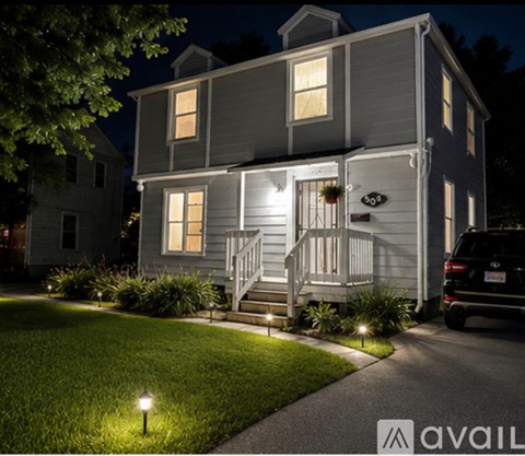 A house with a well-lit front porch and a car parked in the driveway.