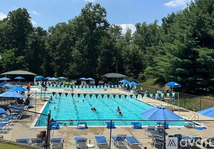A large outdoor swimming pool with people swimming and sunbathing.
