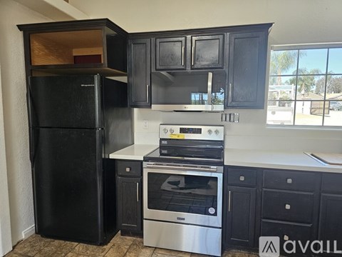 A kitchen with black cabinets and appliances is available for rent.