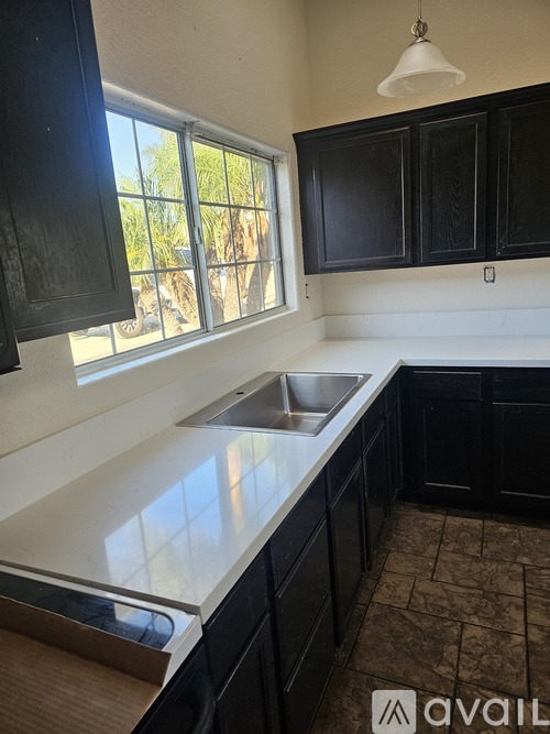 A kitchen with black cabinets and a window.