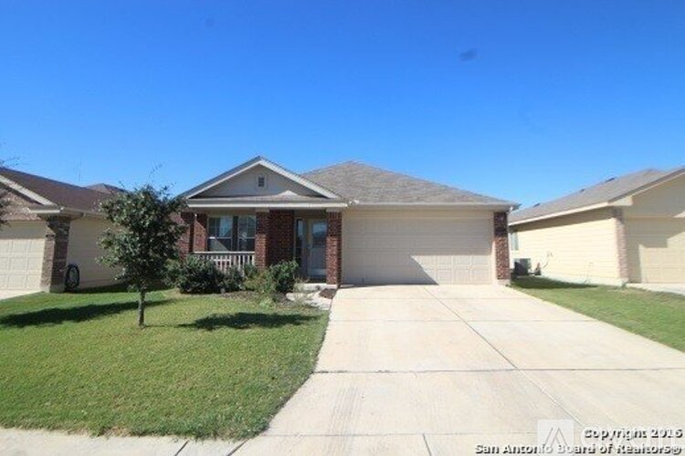 A house with a driveway and a tree in front of it.