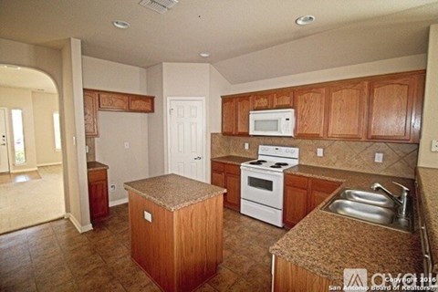 A kitchen with wooden cabinets and a white stove top oven.