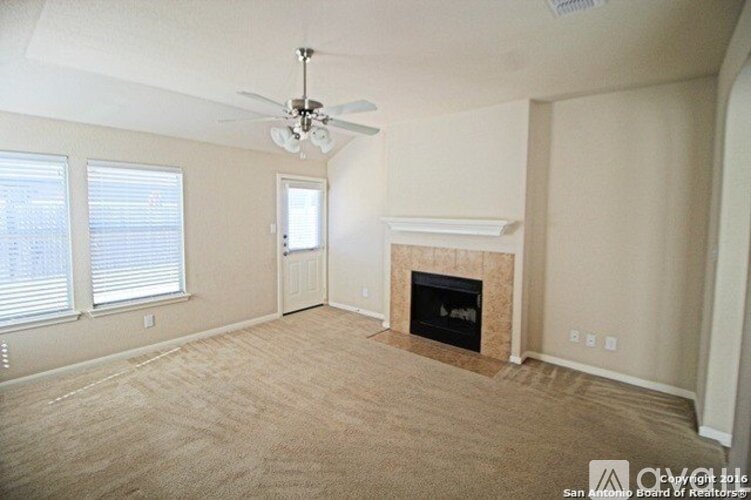 A living room with a fireplace and a ceiling fan.