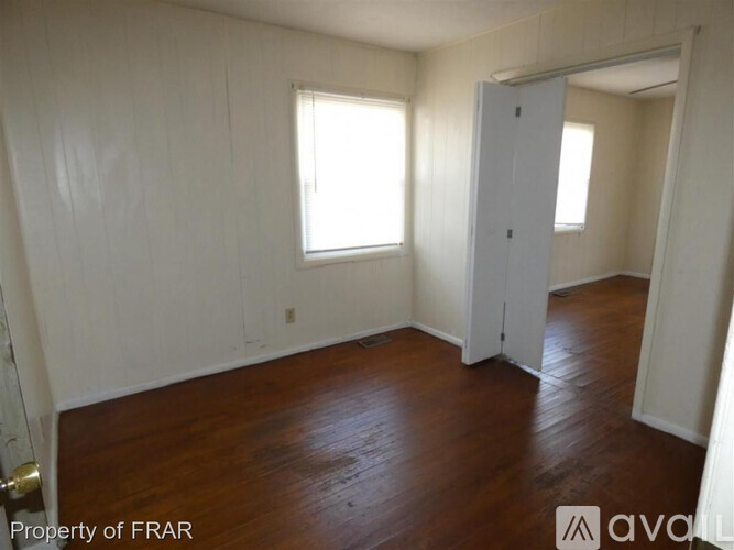 A room with wooden floors and white walls, with a door on the right side.