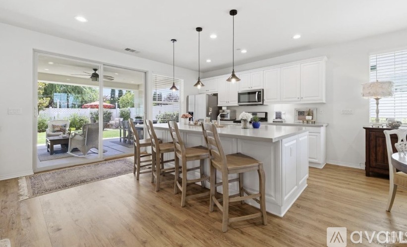 A modern kitchen with wooden floors and white cabinets.