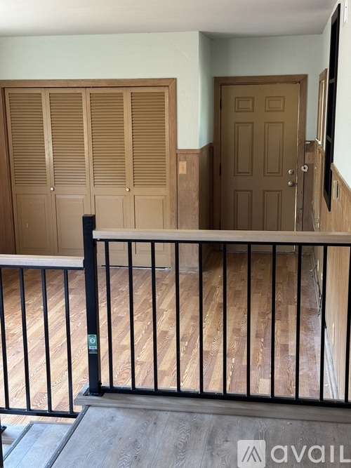 A balcony with a black railing and wooden flooring.