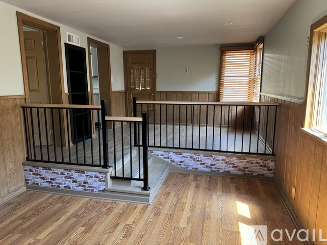 A balcony with a black railing and wooden flooring.